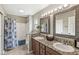 Well-lit bathroom featuring double sinks with granite countertop and tiled shower and tub at 4818 Arabian Run, Indianapolis, IN 46228