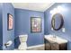 Bathroom with blue walls, decorative mirrors, and updated sink and toilet, offering a modern touch at 4818 Arabian Run, Indianapolis, IN 46228