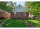 Backyard view of a brick house with green grass and a driveway at 5232 E 10Th St, Indianapolis, IN 46219