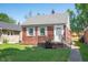 Charming brick home featuring a gray roof, white shutters, and green front lawn at 5232 E 10Th St, Indianapolis, IN 46219