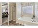 The bathroom features a soaking tub, a shower, wood-look floors, and natural light from a window at 5560 Goodwin St, Indianapolis, IN 46234