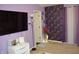 Bedroom with a large screen TV, purple accent wall, and a decorative floor lamp at 6056 Blackley Ct, Indianapolis, IN 46254