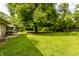 Lush backyard with mature trees, showcasing ample green space and the side of the house at 6220 Spring Mill Rd, Indianapolis, IN 46260