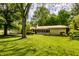 Beautiful backyard showcasing lush lawn, mature trees, and a charming home with a screened porch at 6220 Spring Mill Rd, Indianapolis, IN 46260