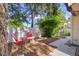 Well-maintained backyard with two red chairs, a small table, mature trees, and a privacy fence at 740 Carya Sq, Columbus, IN 47201