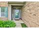 Inviting front entrance with a green door, sidelights, and a 'Welcome' sign, surrounded by lush greenery at 7452 Lace Bark Ct, Avon, IN 46123