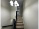 Carpeted stairs with a dark railing lead to the upper level with a decorative light fixture at 7514 Ruskin Pl, Indianapolis, IN 46226