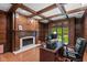 Spacious home office with wood trim, fireplace, and a view of the landscaped backyard at 7624 William Penn Pl, Indianapolis, IN 46256
