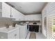 Bright laundry room featuring white cabinets, a utility sink, washer, dryer, and natural light from a window at 7624 William Penn Pl, Indianapolis, IN 46256