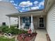 Inviting covered porch with rocking chairs, flower planters, and a decorative wreath on the front door at 7733 Sergi Canyon Dr, Indianapolis, IN 46217