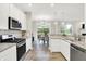 Bright kitchen featuring white cabinets, stainless steel appliances, and an open dining area at 8266 Glacier Ridge Dr, Fishers, IN 46038