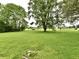 Lush green lawn with mature trees and benches in a backyard setting at 9098 W 1050 N, Elwood, IN 46036
