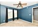 Well-lit bedroom with plush carpet, a ceiling fan, and large windows, painted in a striking blue tone at 924 S B St, Elwood, IN 46036