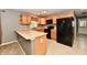 Well-lit kitchen features wood cabinets, black appliances, and a breakfast bar for casual dining at 924 S B St, Elwood, IN 46036