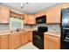 Functional kitchen features light wood cabinetry, black appliances, and ample countertop space by the window at 924 S B St, Elwood, IN 46036