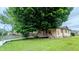 Charming single-story home with large mature shade tree and wooden ramp to the covered porch at 100 N 6Th Ave, Beech Grove, IN 46107