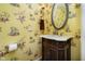Unique powder room features monkey toile wallpaper, vanity with marble countertop, and oval mirror at 10627 Indian Lake S Blvd, Indianapolis, IN 46236