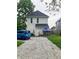 Back exterior view showing parking area, small covered patio, and fenced yard at 1114 N Olney St, Indianapolis, IN 46201