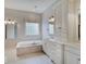 Bright bathroom featuring a soaking tub, double vanity, and linen storage at 11521 Willow Bend Dr, Zionsville, IN 46077