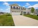 Two-story home featuring a two-car garage, tan siding, black shutters and a well-maintained green lawn with a long driveway at 13887 N Hawkers Hill Dr, Camby, IN 46113