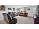 Cozy living room featuring comfortable leather sofas, plush carpeting, and warm natural light from a window at 13887 N Hawkers Hill Dr, Camby, IN 46113