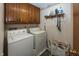 Functional laundry room equipped with washer, dryer, and upper storage cabinets at 1602 Queensbridge Sq # 7, Indianapolis, IN 46219