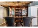Basement bar area featuring dark wood cabinetry, glass shelving, and comfortable seating at 16126 Etna Green, Westfield, IN 46074