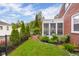 Well-manicured backyard with green lawn, lush garden beds, brick path, and an enclosed sunroom addition to the home at 2021 Chestnut St, Columbus, IN 47201