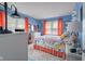 Bright bedroom featuring bold blue walls, colorful floral bedding, and ample natural light, creating a cheerful space at 2021 Chestnut St, Columbus, IN 47201