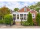 Exterior view of home with a sunroom addition, landscaped garden beds, and a charming brick facade at 2021 Chestnut St, Columbus, IN 47201