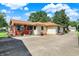 Exterior view of house featuring a red sunroom, vinyl siding, mature trees, front deck and an asphalt driveway at 2110 Fisher Ave, Speedway, IN 46224