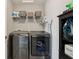 Convenient laundry room with modern washer and dryer, storage shelf, and ironing supplies at 220 Sawdust Trl, Greenfield, IN 46140
