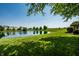 Peaceful pond view with green lawn, a small deck, and residential houses in the distance at 2209 S Logan Dr, New Palestine, IN 46163