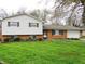 Traditional home featuring brick and white siding, complemented by green shutters and a lush green lawn at 2414 Constellation Dr, Indianapolis, IN 46229