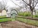 Backyard shed with rustic charm, featuring double doors and white-trimmed windows set against a fenced yard at 2414 Constellation Dr, Indianapolis, IN 46229