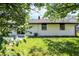 White home with fenced yard, small patio, and trees at 3237 Thurston Dr, Indianapolis, IN 46224