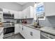 Well-lit kitchen features white cabinets, stainless steel appliances, granite countertops, and a view from the window at 353 S Indiana St, Danville, IN 46122