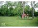 A backyard with a playground featuring a slide and climbing wall, surrounded by green grass at 4023 Cedar Hills South Dr, Greenwood, IN 46143