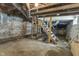 An unfinished basement with exposed wooden stairs, ducts, and concrete foundation at 418 Harlan St, Indianapolis, IN 46201