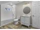 A stylish bathroom featuring wood flooring, subway tile, and a modern round mirror at 418 Harlan St, Indianapolis, IN 46201
