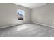 A bright bedroom with gray carpet and a window providing a view of the neighborhood at 418 Harlan St, Indianapolis, IN 46201