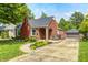Charming brick home featuring mature trees, landscaped yard, and a detached garage with paved driveway at 5809 N Illinois St, Indianapolis, IN 46208