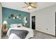 Well-lit bedroom features a ceiling fan, decorative accent wall, carpet flooring, and a view of a black paneled door at 5850 Lyster Ln, Indianapolis, IN 46239