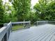 Large backyard deck with grey wood and railing with a green view of the backyard forest at 6538 N Tutterow Rd, Monrovia, IN 46157