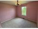 Bedroom features pink walls, neutral carpet, a ceiling fan, and a window overlooking a lawn at 660 White Ash Trail, Mooresville, IN 46158