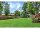 The backyard features a lush lawn, mature trees, and a wooden fence, creating a serene outdoor space at 6605 Grosvenor Pl, Indianapolis, IN 46220