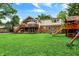 Spacious backyard with lush lawn, mature trees, playset, and deck, perfect for outdoor enjoyment and entertaining at 6605 Grosvenor Pl, Indianapolis, IN 46220