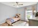 Bright bedroom featuring wood floors, a ceiling fan, a twin bed, and a window with colorful curtains at 6605 Grosvenor Pl, Indianapolis, IN 46220