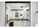This shower has a glass door, tiled walls with black accents, and a shower head with hand-held attachment at 6605 Grosvenor Pl, Indianapolis, IN 46220