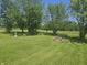 A spacious backyard featuring mature trees, green grass, and a cozy fire pit at 705 S 450 E, Franklin, IN 46131
